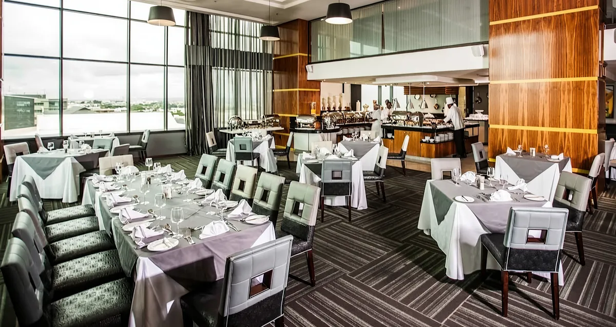 Hotel restaurant with laid tables and an open kitchen behind