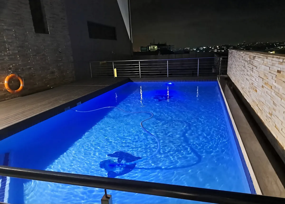 Rooftop pool lit blue at night above the city